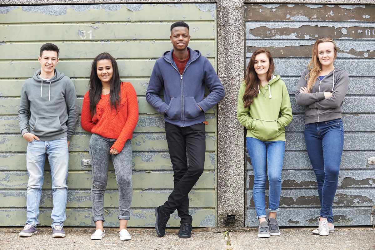 5 young people stood against a wall