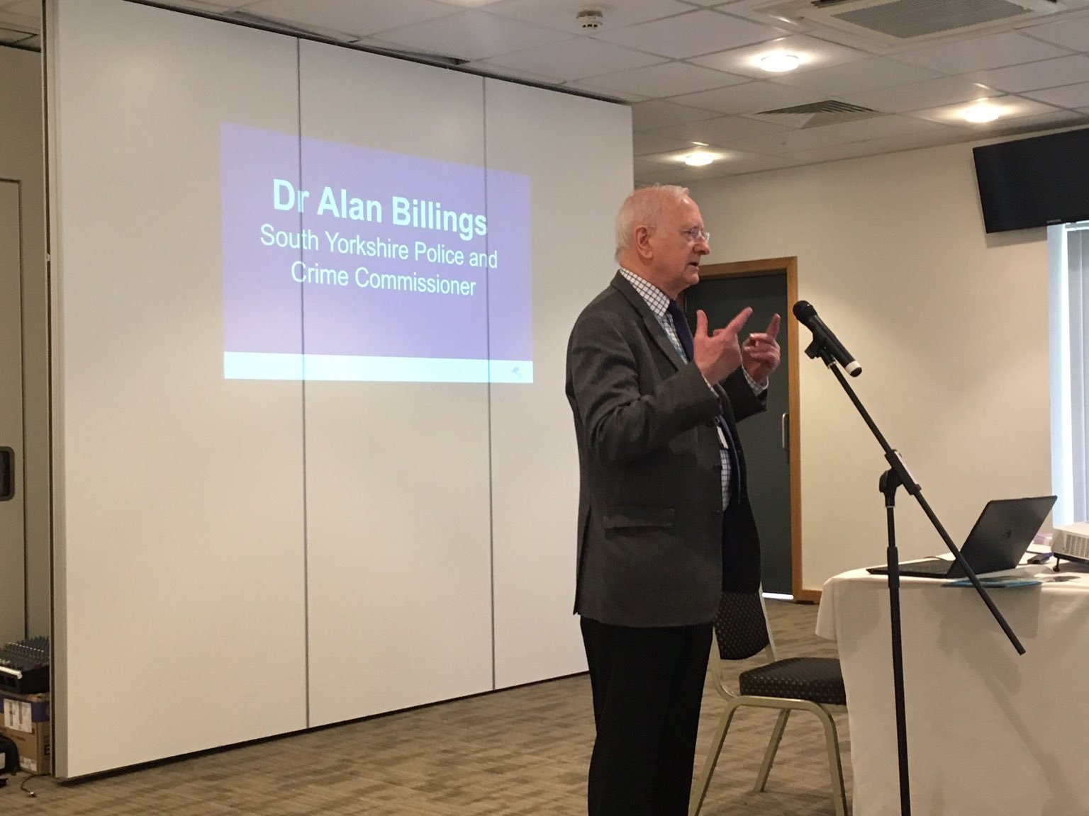 Dr Alan Billings speaking into a microphone