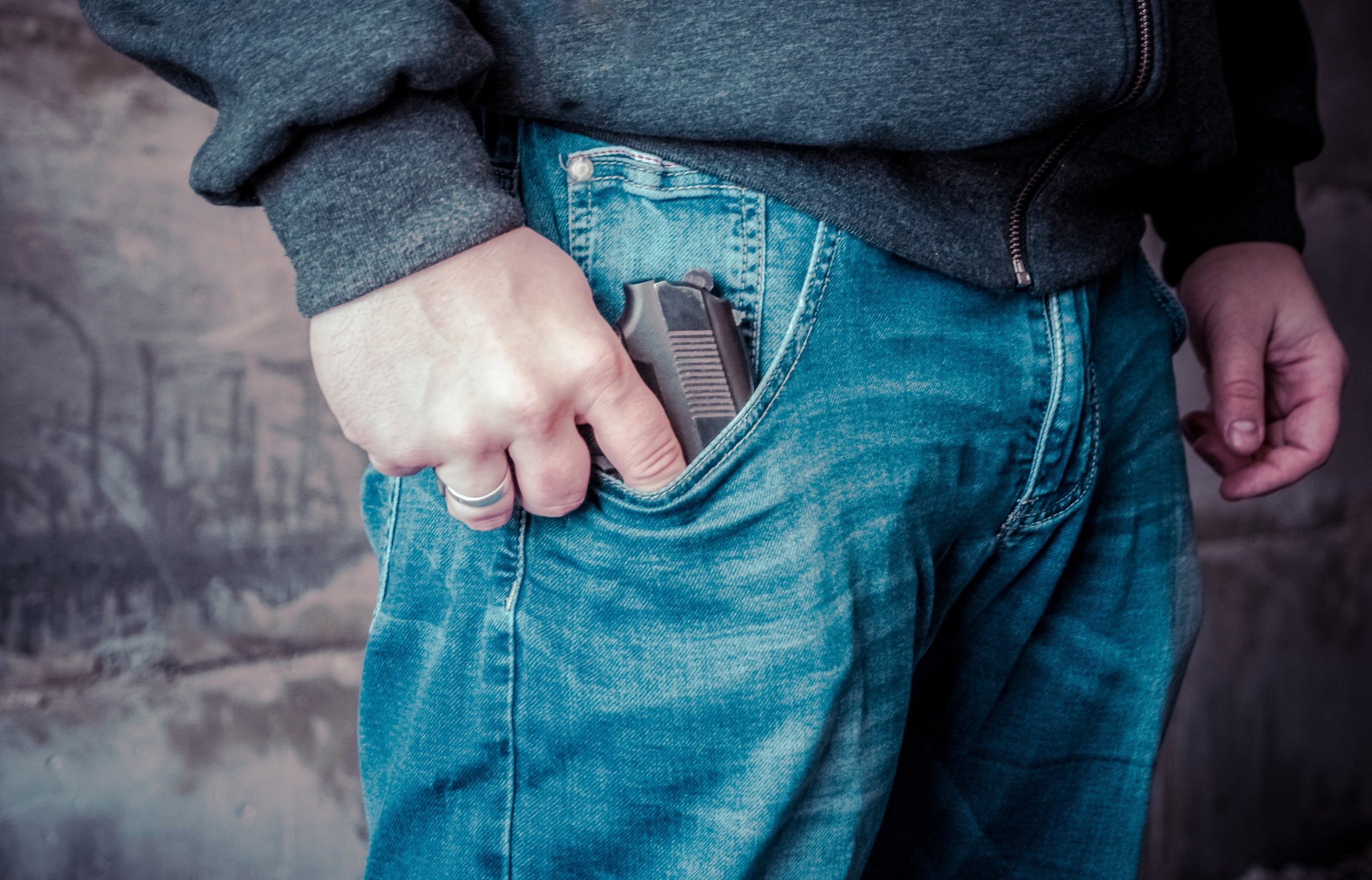 A person holding a gun inside a jeans pocket