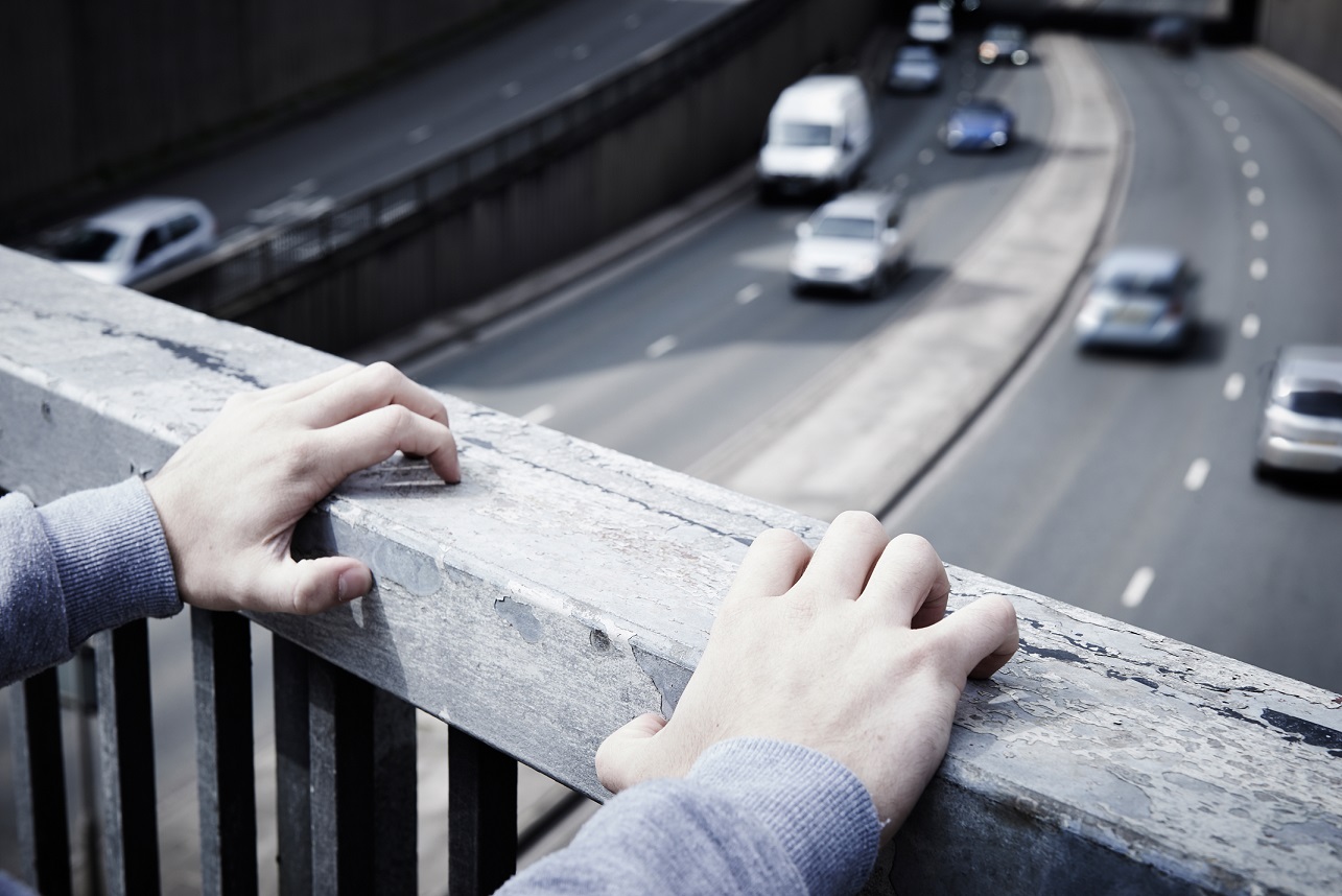Hands on the rail of a bridge
