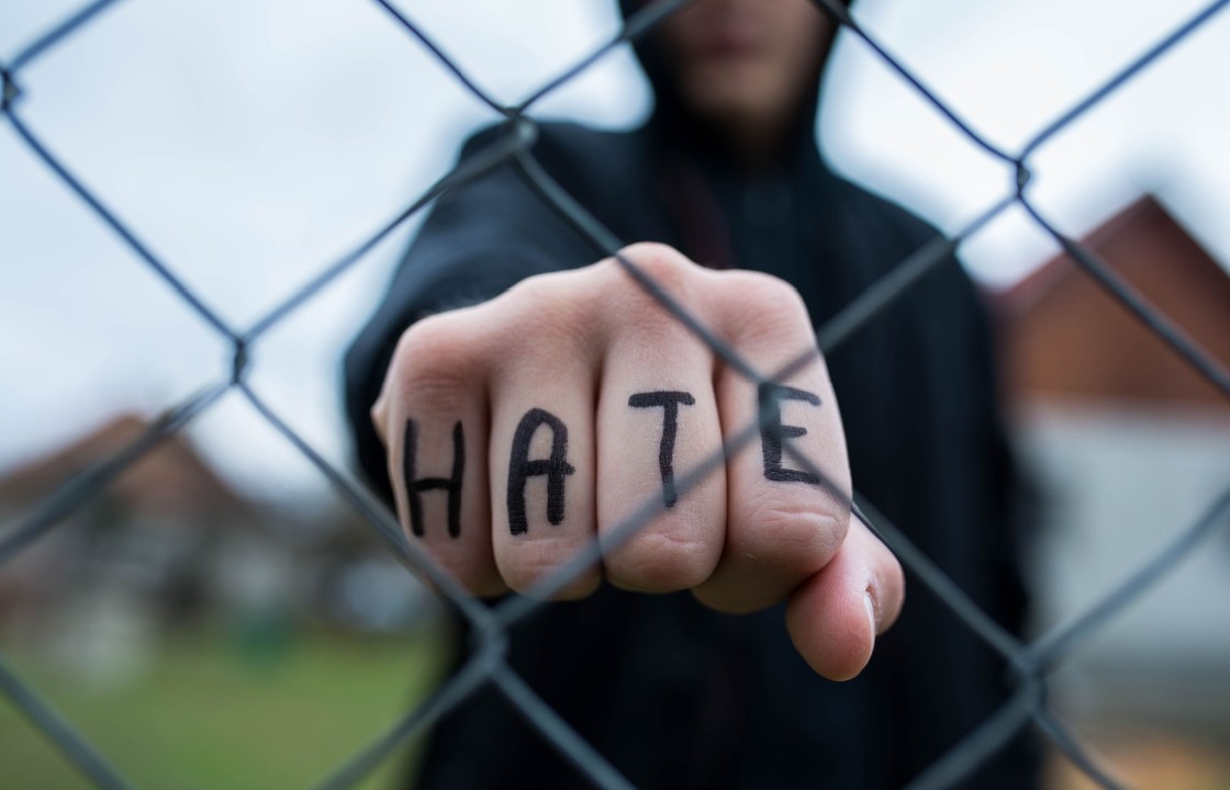 A person making a fist with the word 'hate' written on their knuckles